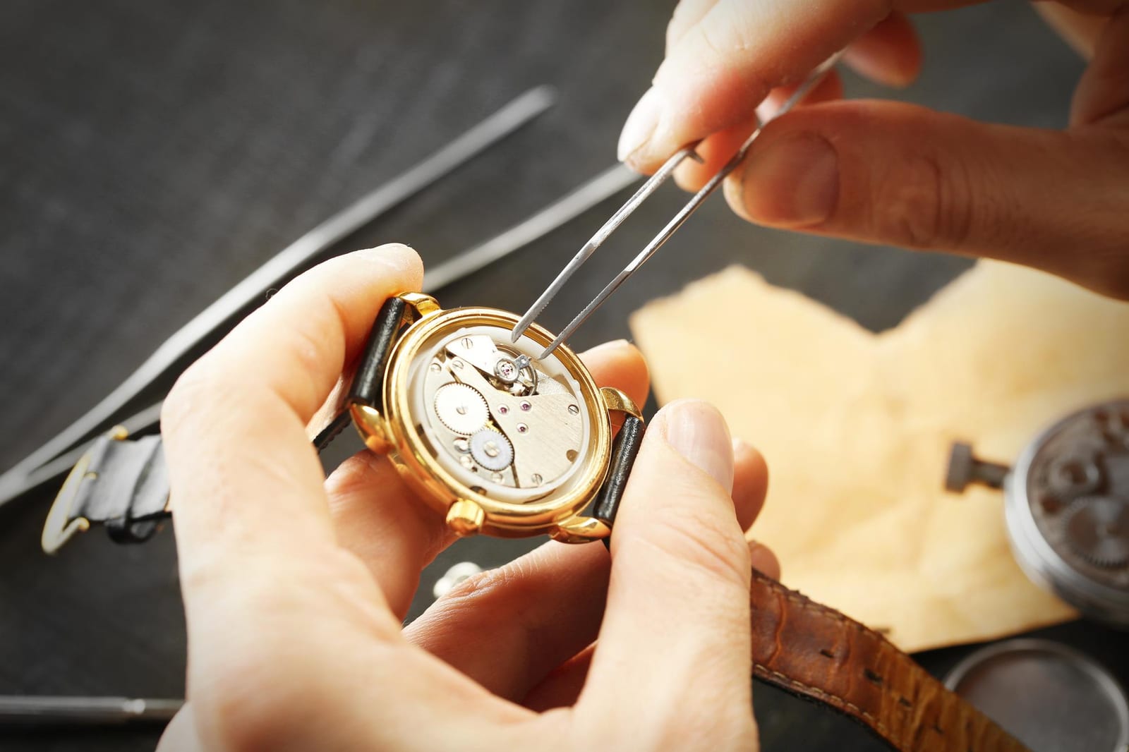 Mani di un orologiaio che intervengono con precisione su un vecchio meccanismo